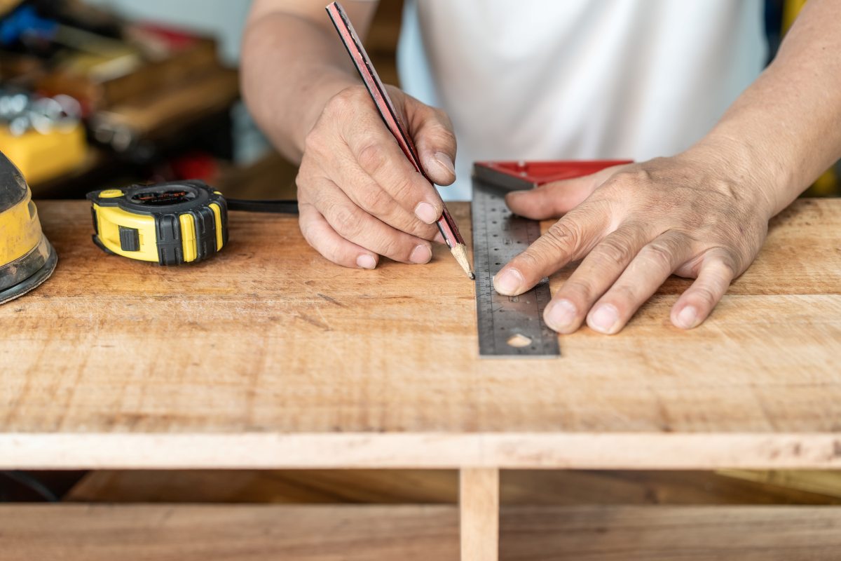 man using a pencil marking the line on wood